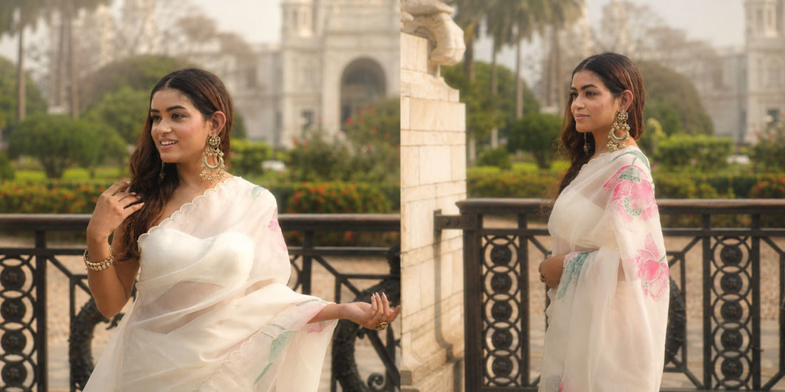 Elegant ivory organza saree featuring traditional hand-painted Pichwai art motifs of holy cows and blooming lotuses.